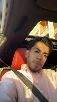 a man in a pink shirt sitting in a car